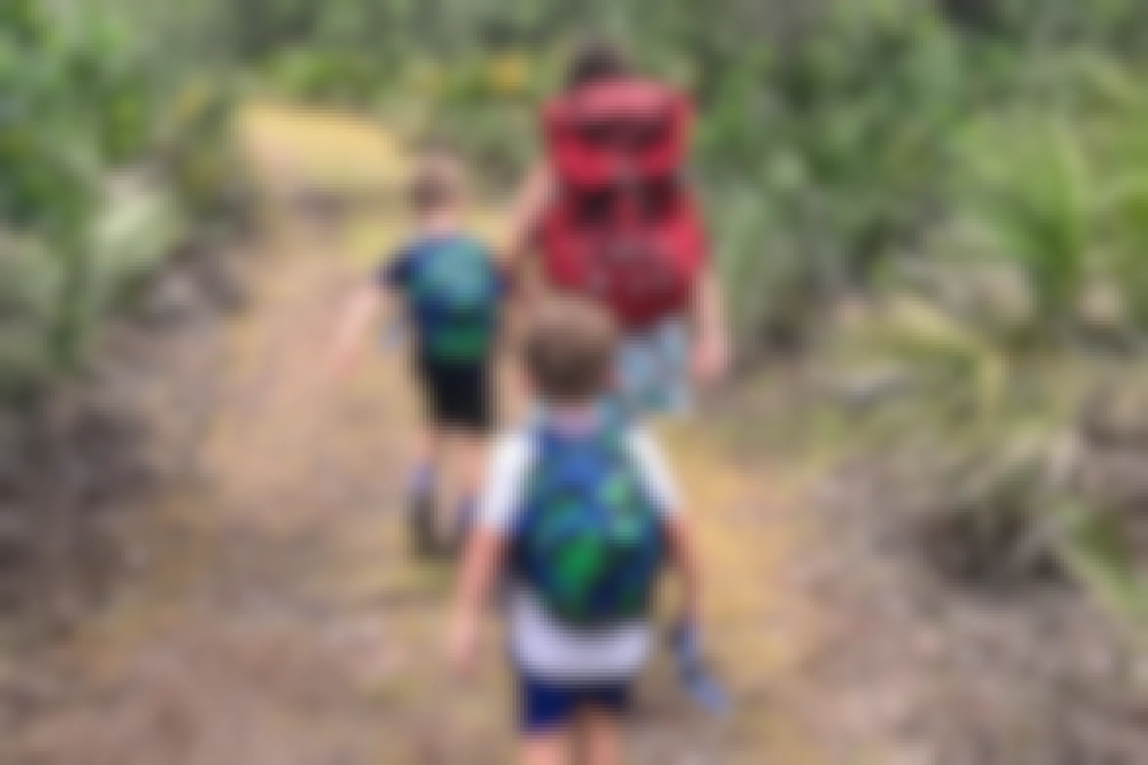 A mom and her kids walking down a nature path, the kids wearing The North Face Sprout backpacks.