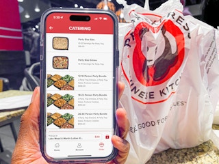 Someone holding a phone displaying the Panda Express app's page for catering