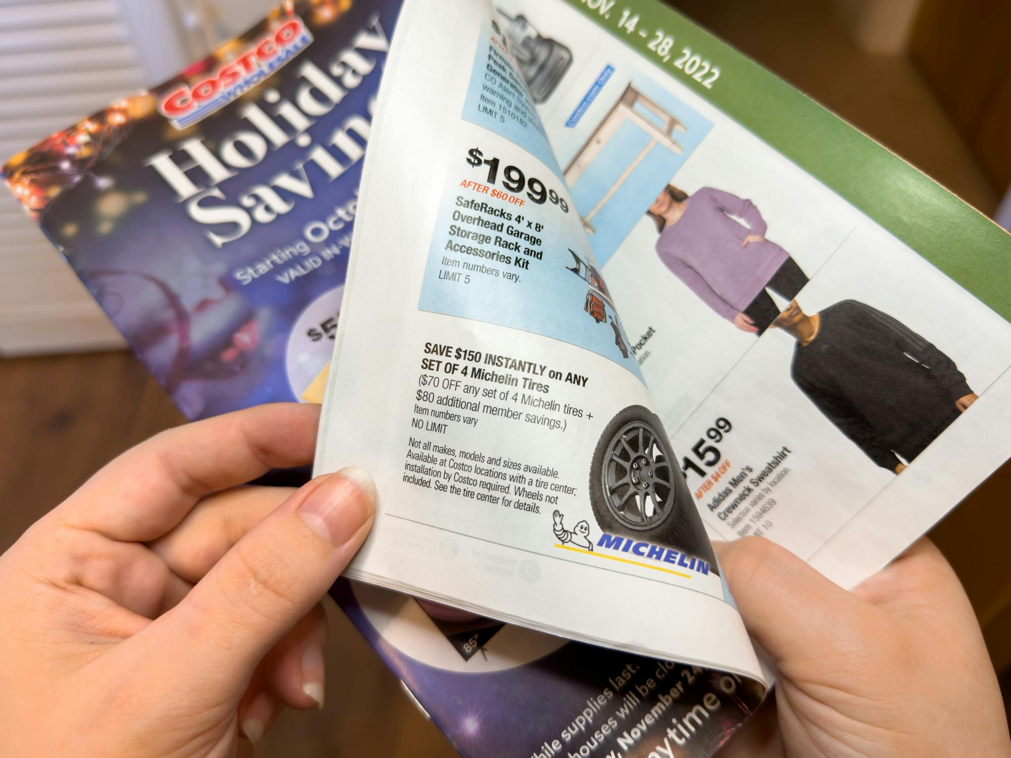 Someone flipping through a Costco Holiday Savings booklet showing the tire deal for Black Friday 2022