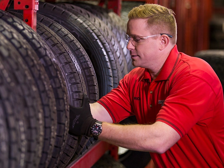 A Discount Tire employee taking a tire from a shelf