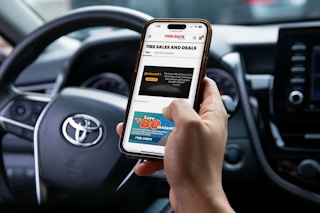 A person sitting in their parked car, looking up tire deals on TireRack.com