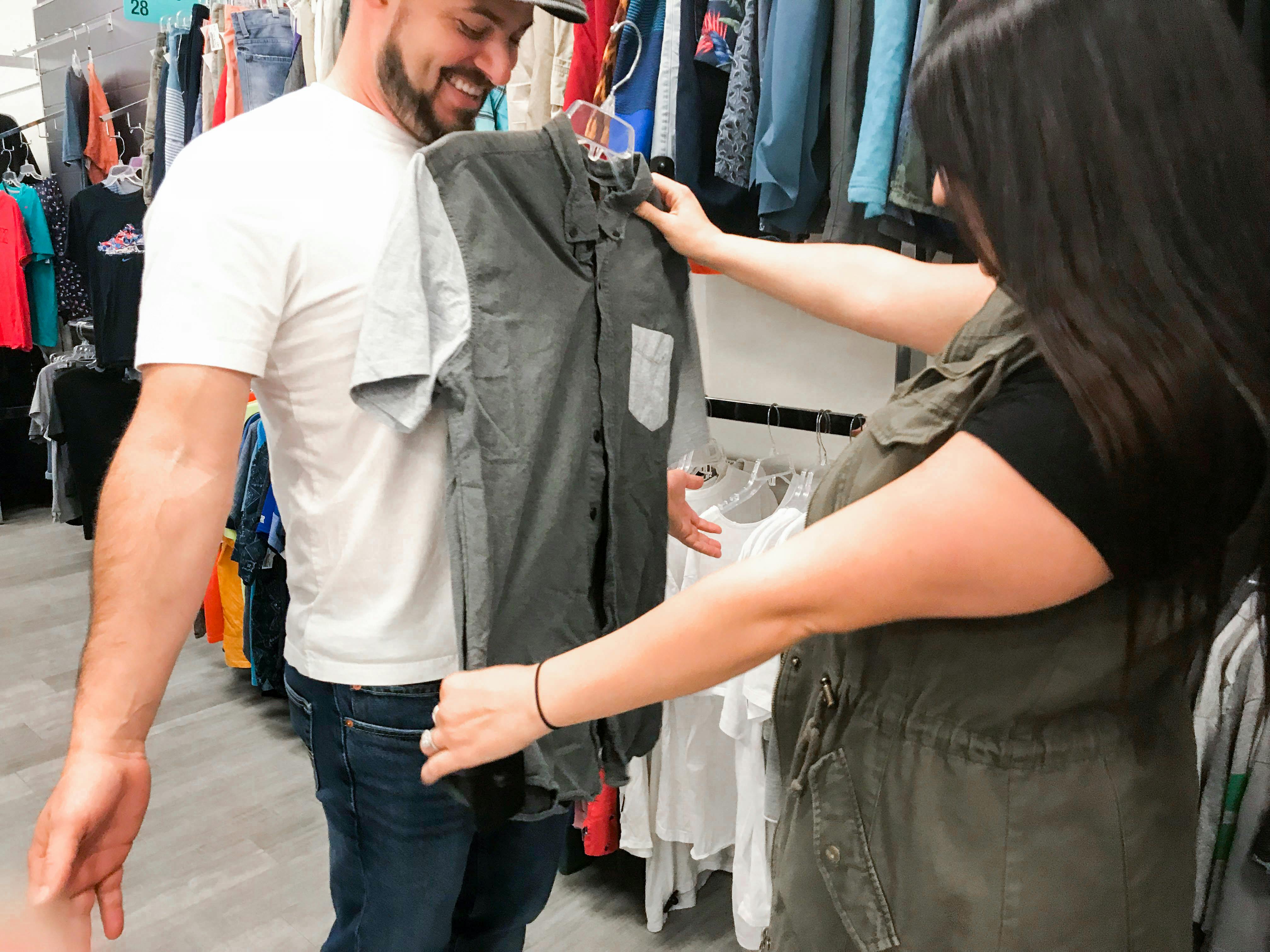 A woman holding up a shirt to a man to assess the size at Plato's closet