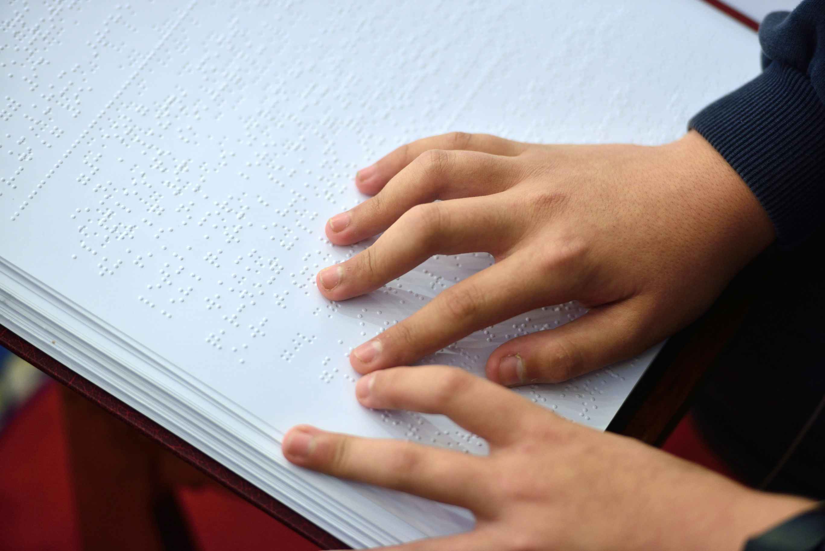 A child's hands going over the page of a braille book.