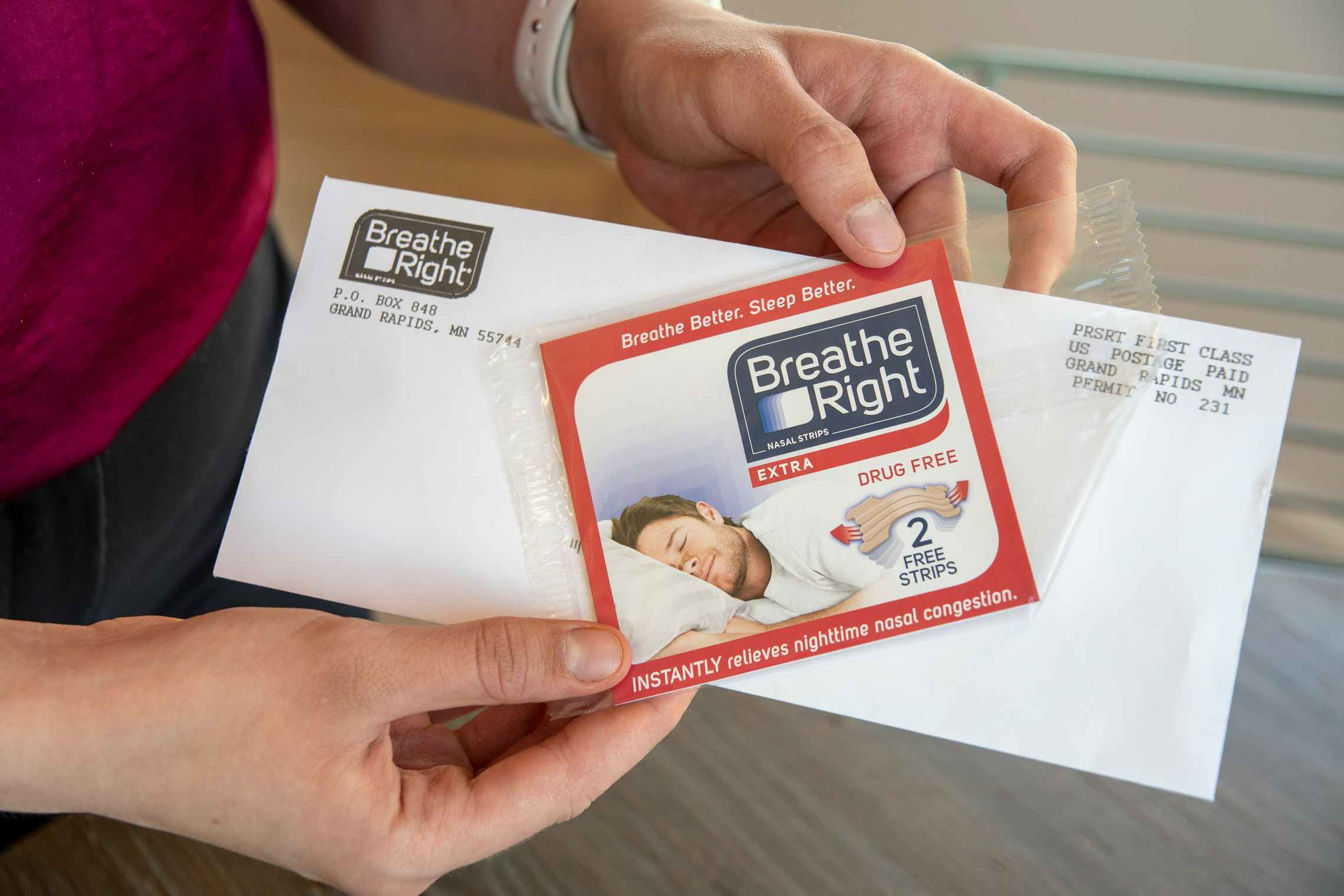 A woman holding an envelope with a free sample of Breathe Right nasal strips.