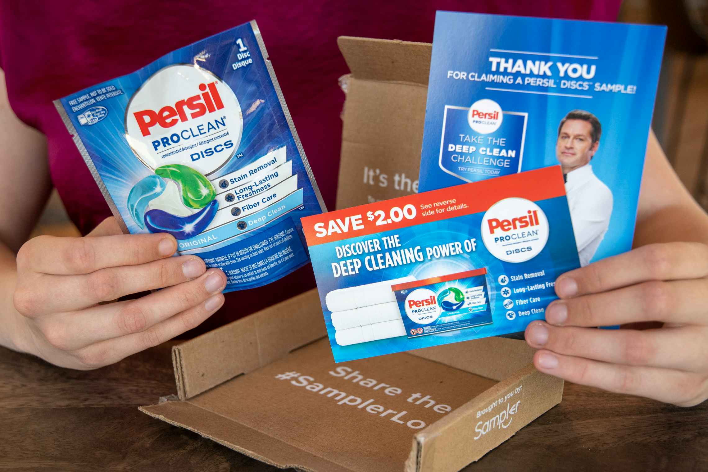 A woman holding a coupon, advertisement, and pouch with a free sample of Persil proclean discs.