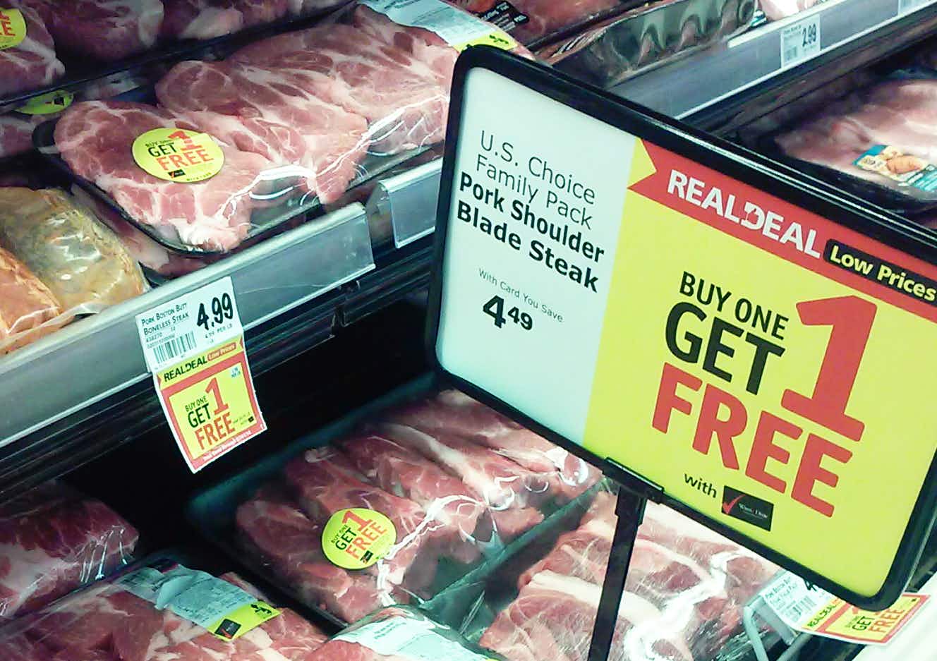 A Buy One Get One promotion sign in a store's meat section.