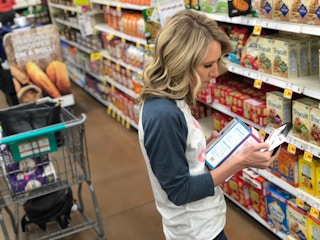A woman shopping in walmart using coupons in the crackers aisle