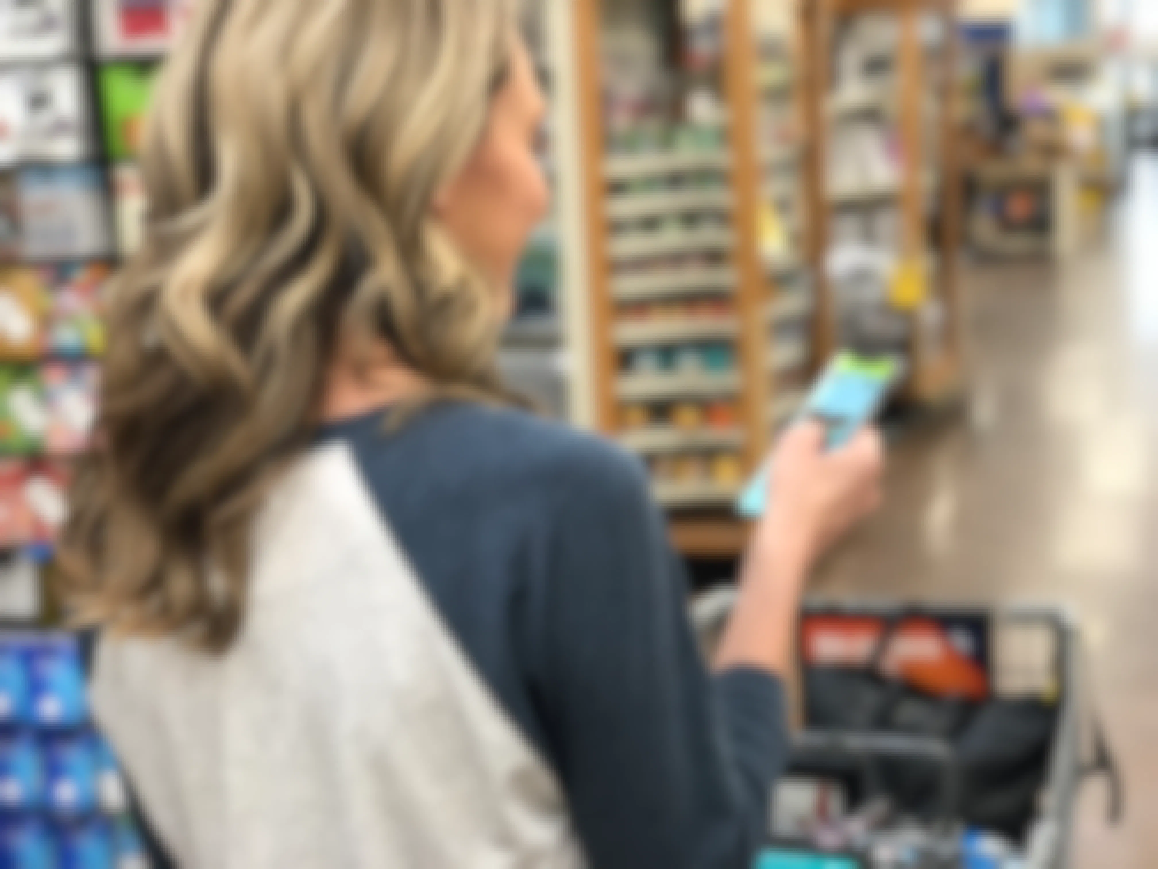 A woman shopping in a store, looking at the KCL app for couponing tips