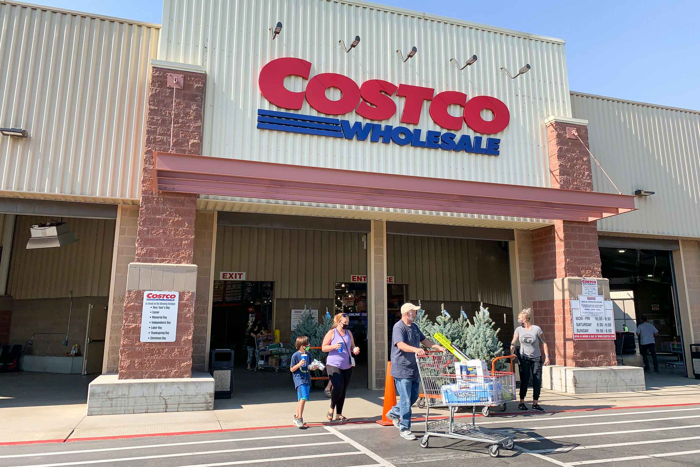 Costco store front with people exiting with a cart full of purchased goods.
