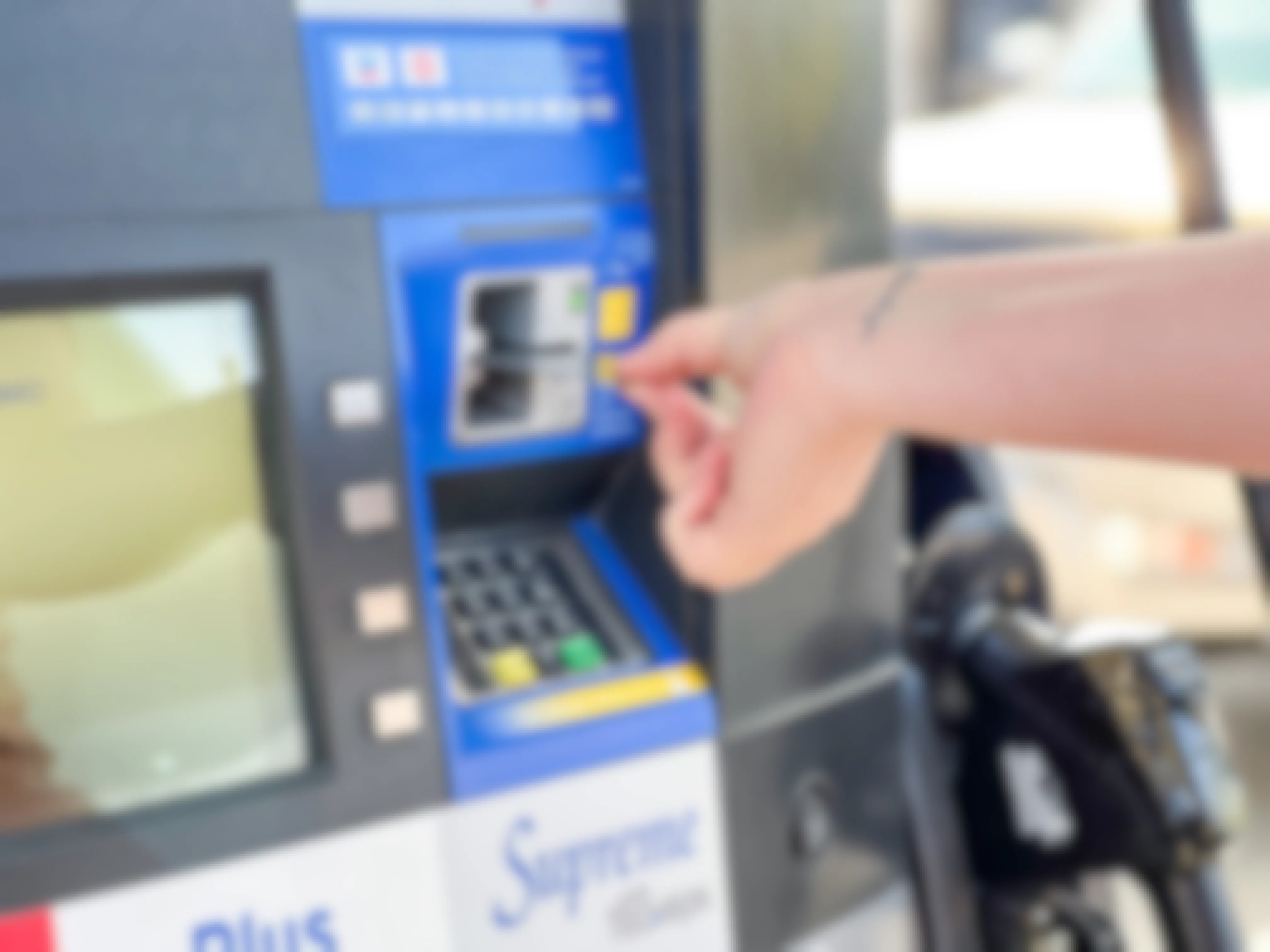 A person's hand putting their credit card into the card reader at a gas pump.