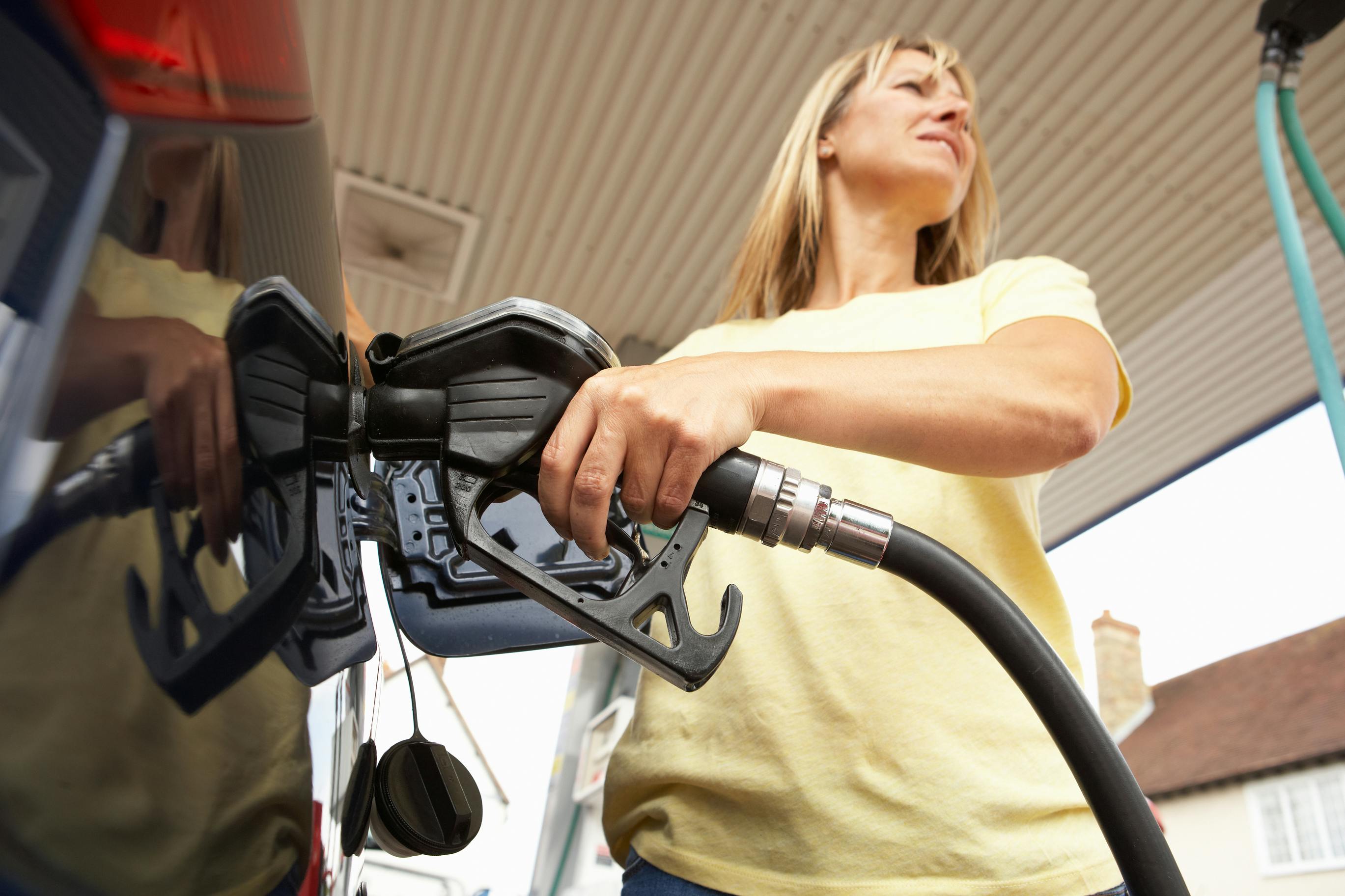 A person inserting a gas pump nozzle into their car to fill the tank.