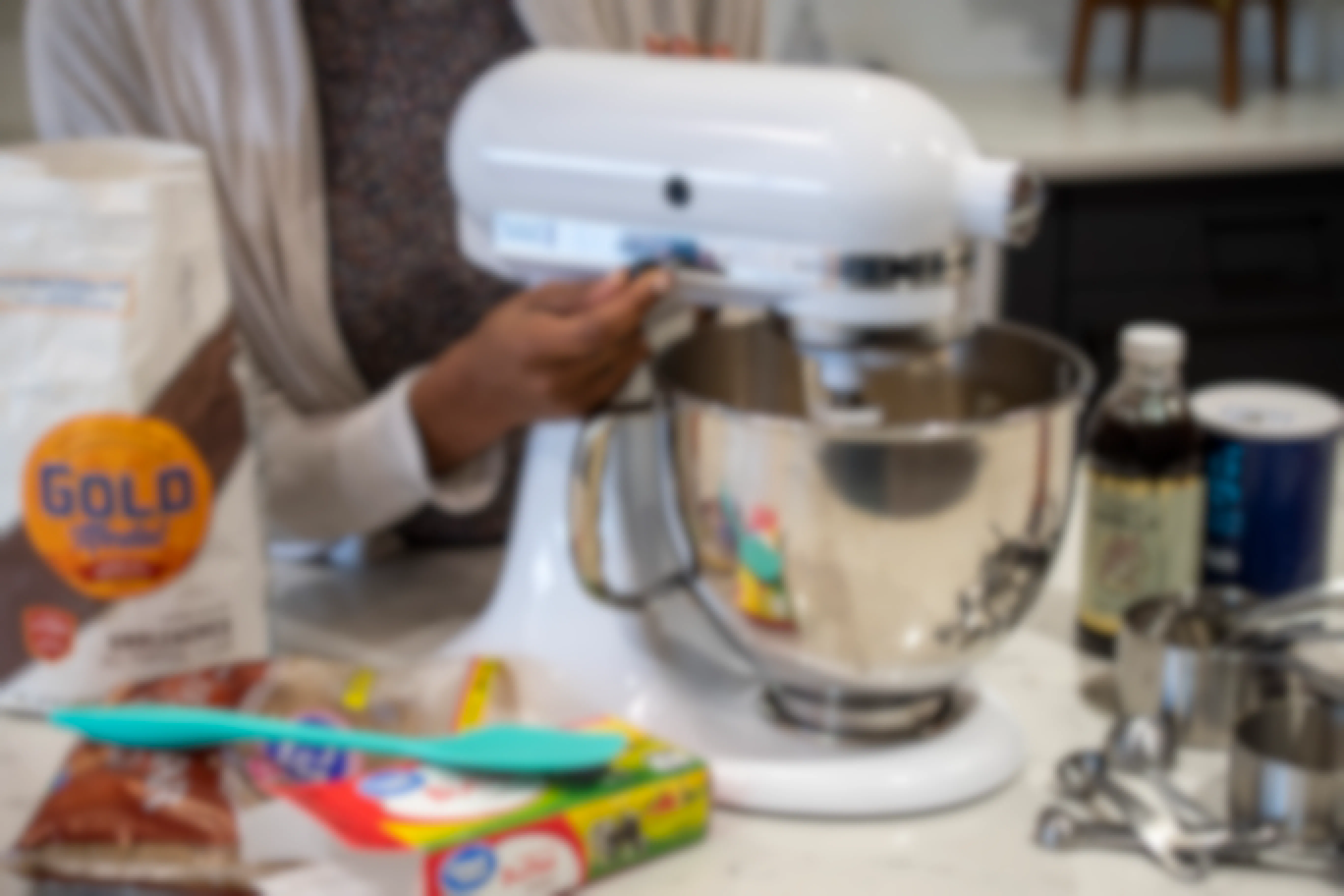 A person mixing ingredients inside a KitchenAid stand mixer.