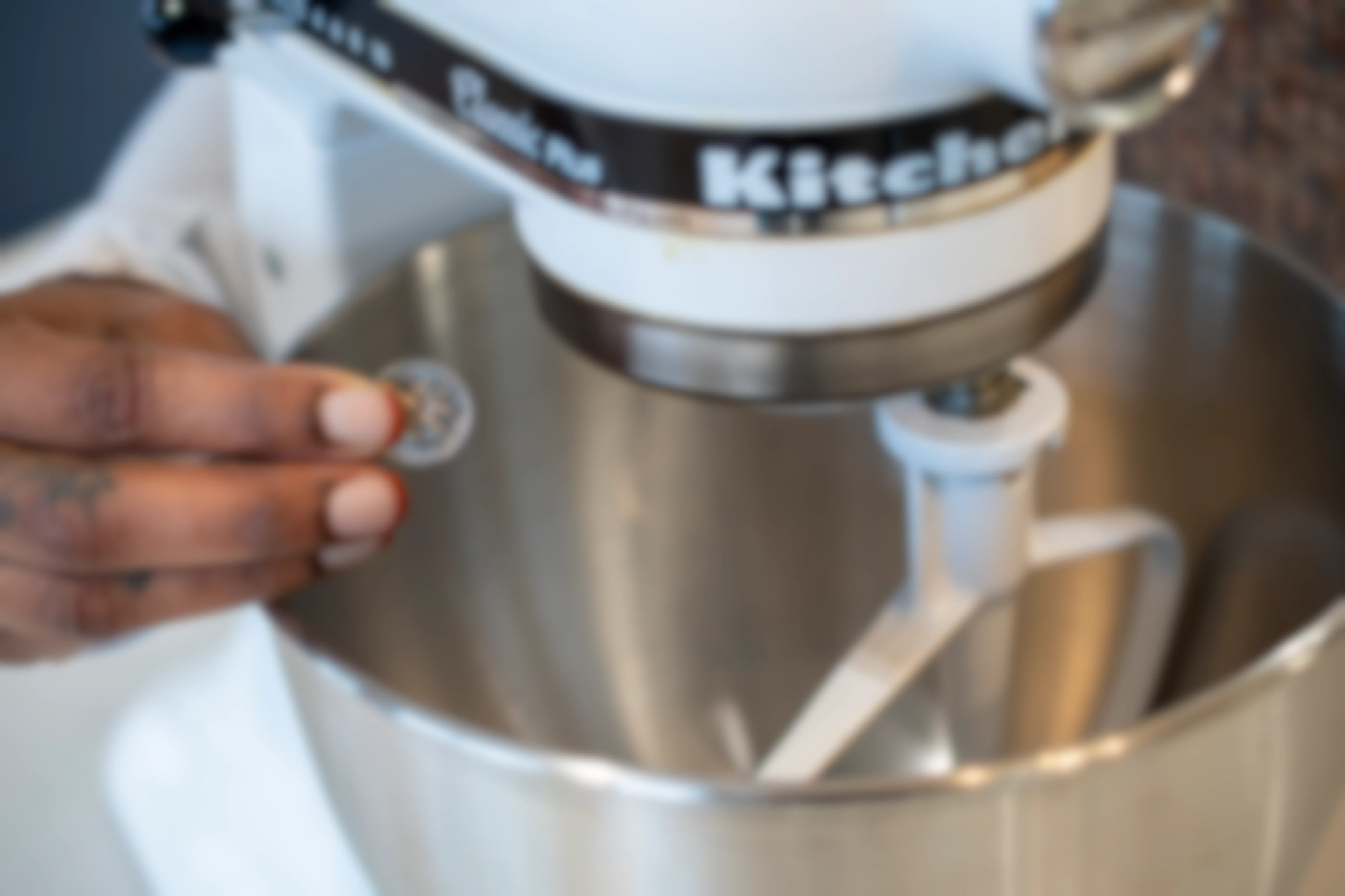 A person holding a dime next to a KitchenAid mixer