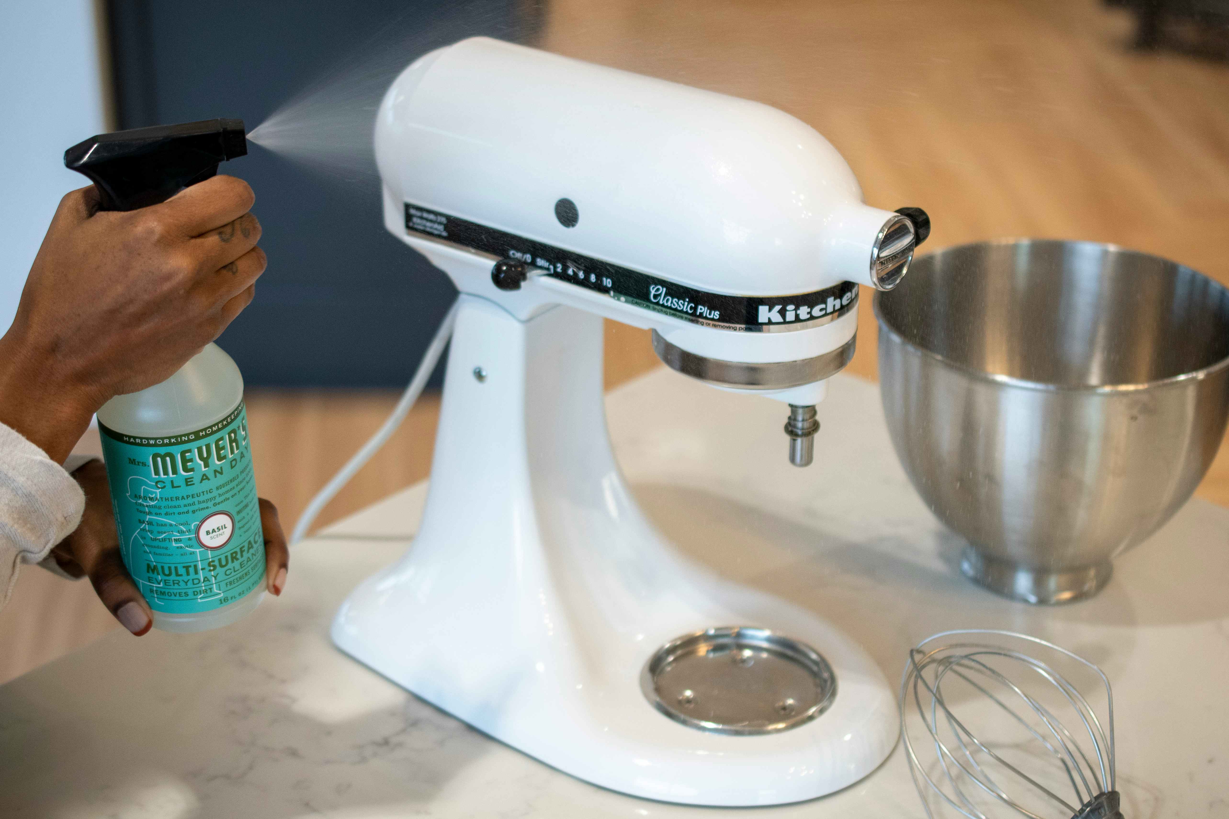 A person spraying Myers Cleaner on the outside of a kitchen aid mixer