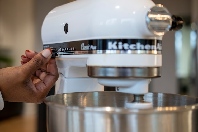 A person turning on a KitchenAid mixer
