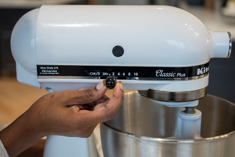 A person turning on a KitchenAid mixer