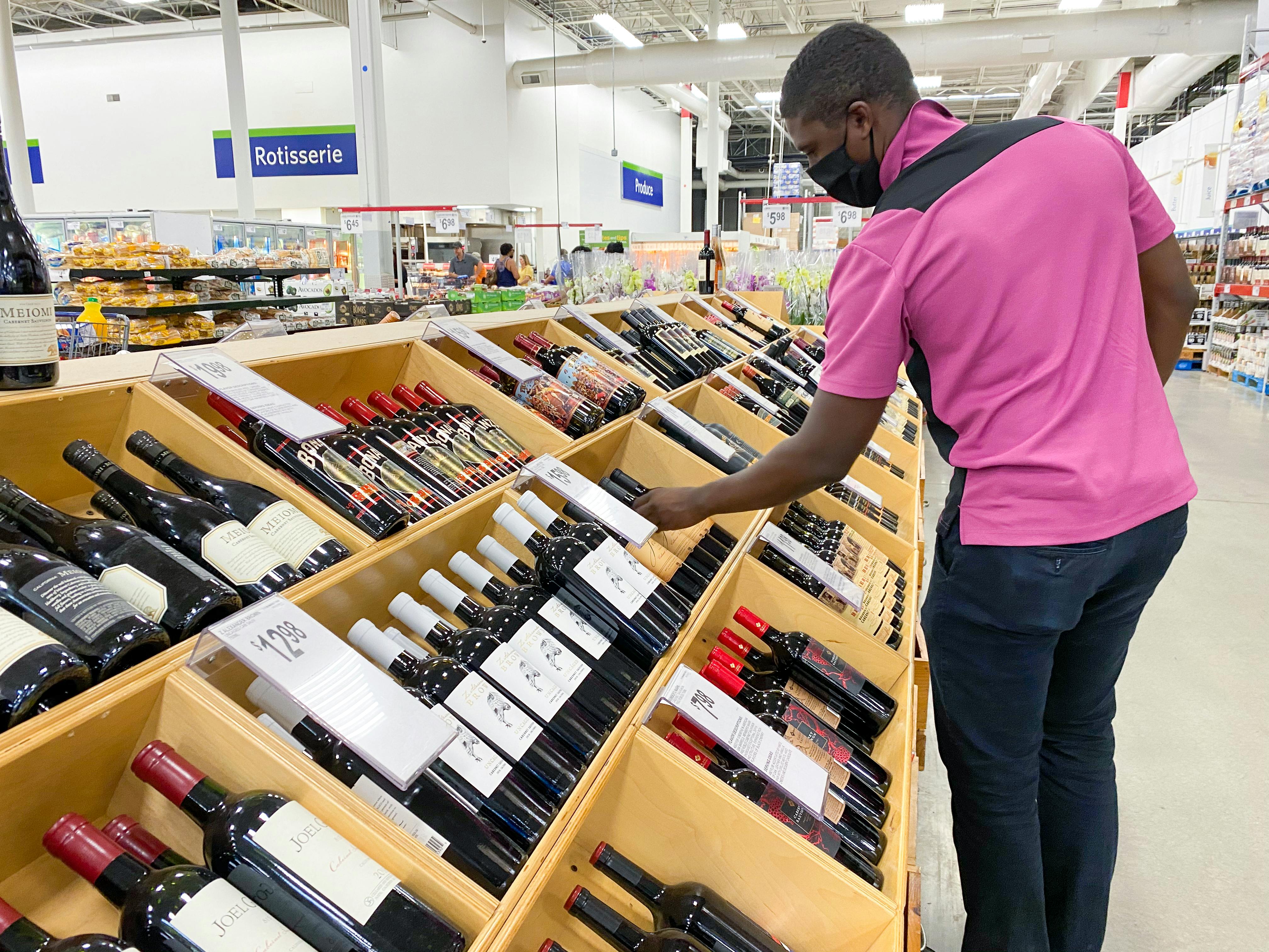 a man looking at wine in the alcohol section