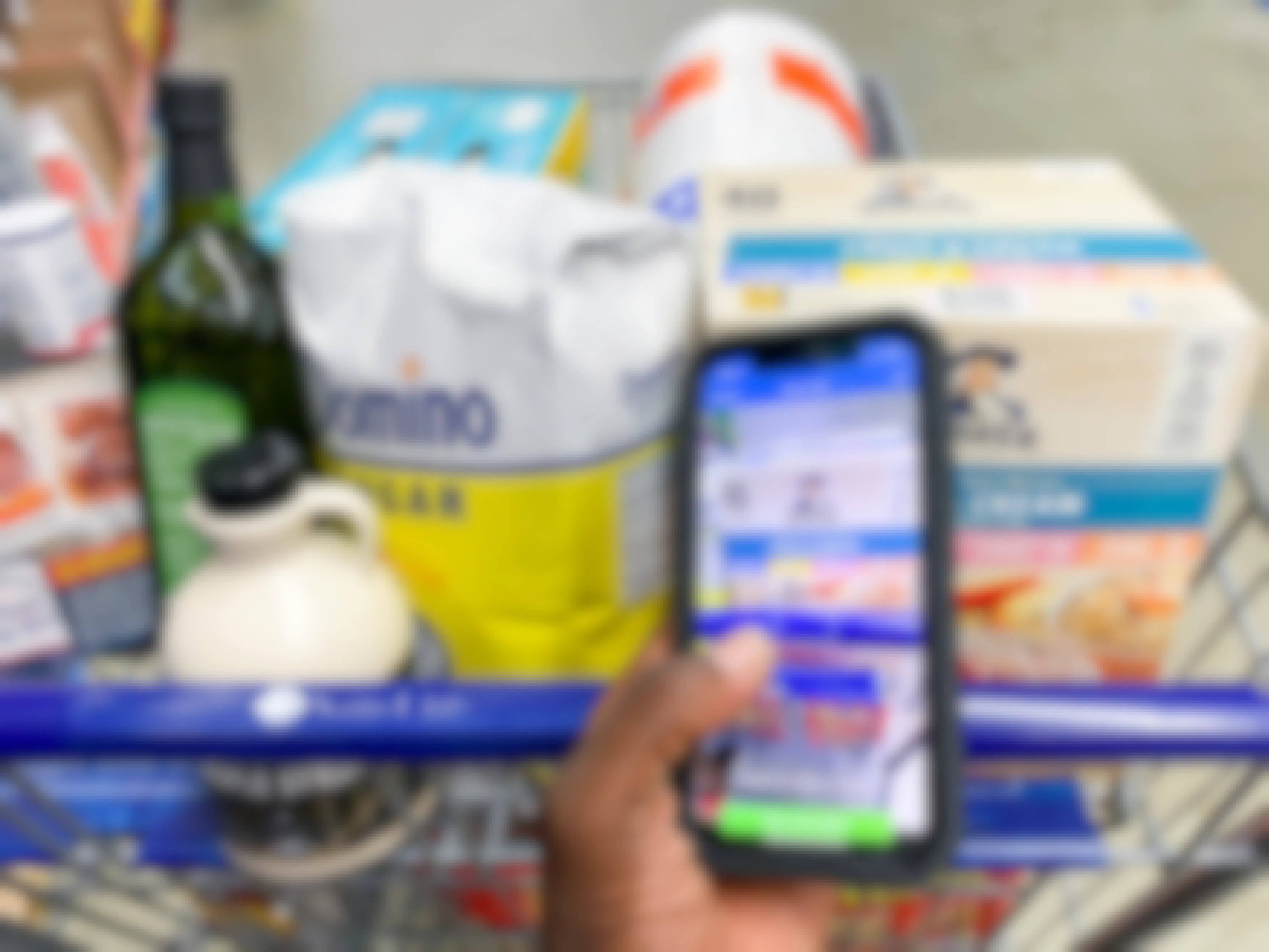 phone held in hand scanning a box of instant oatmeal inside a shopping cart full of groceries