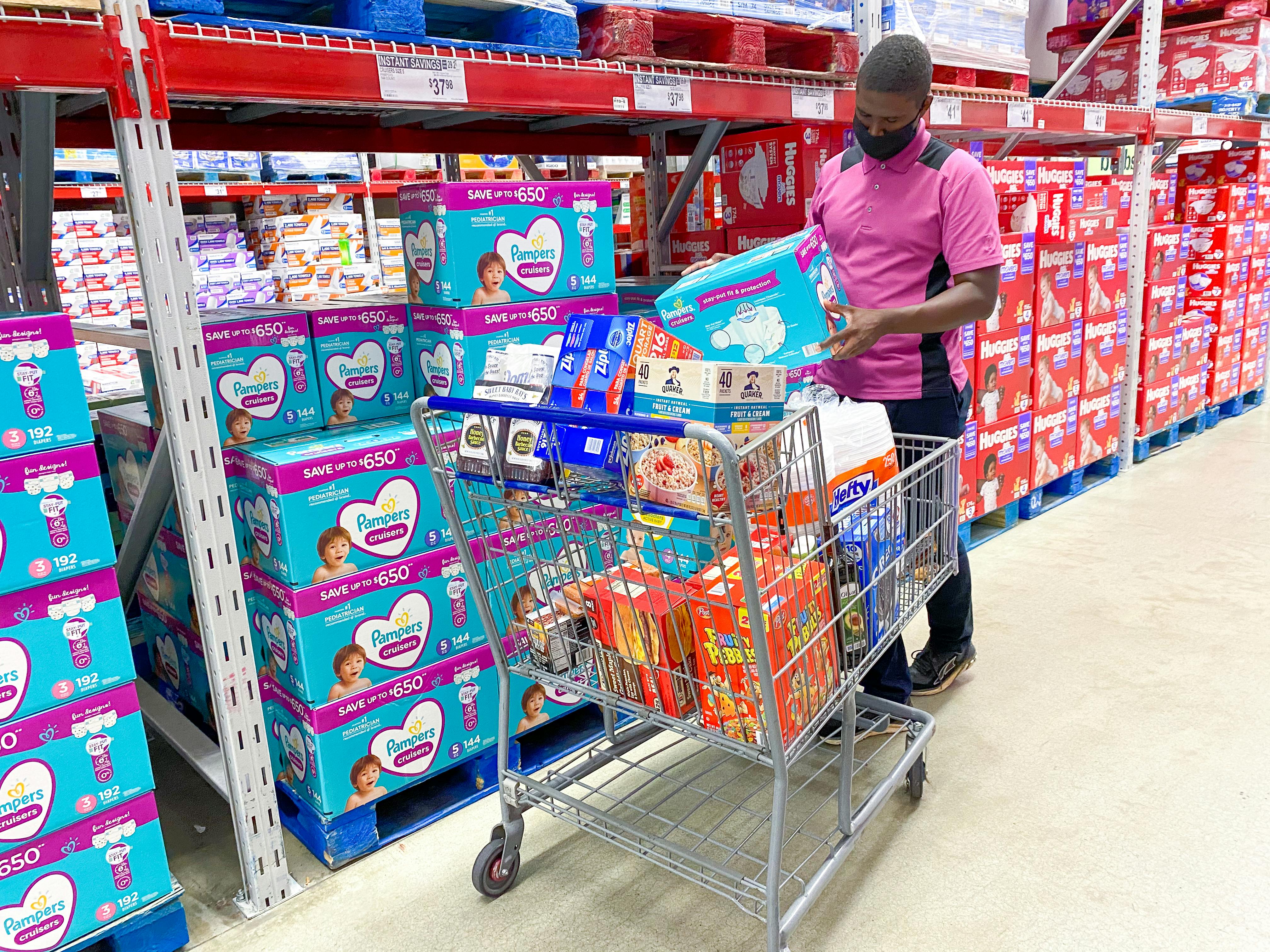 man in diaper aisle putting a box full of diapers into his cart