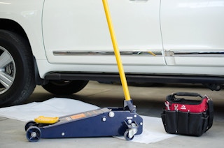 A car with a jack next to it and a toolbox.