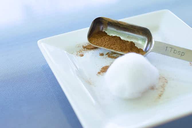 A tablespoon with cinnamon on a plate with a cotton ball