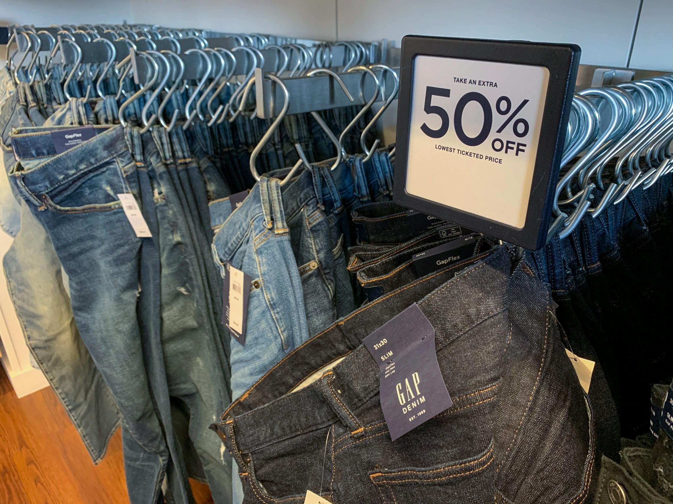 A row of mens demin jeans bellow a sign that say 50% off.