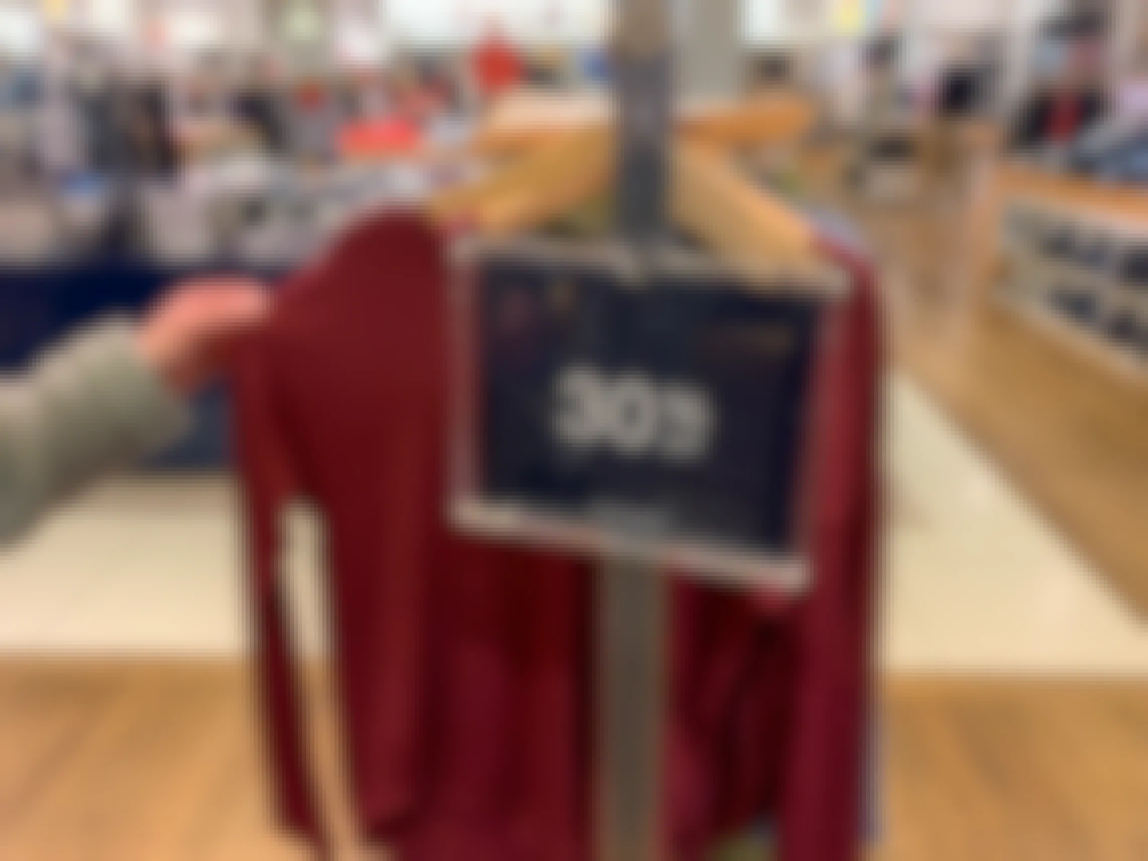 A sales rack with burgundy long sleeve shirts with a sign that reads 30% off