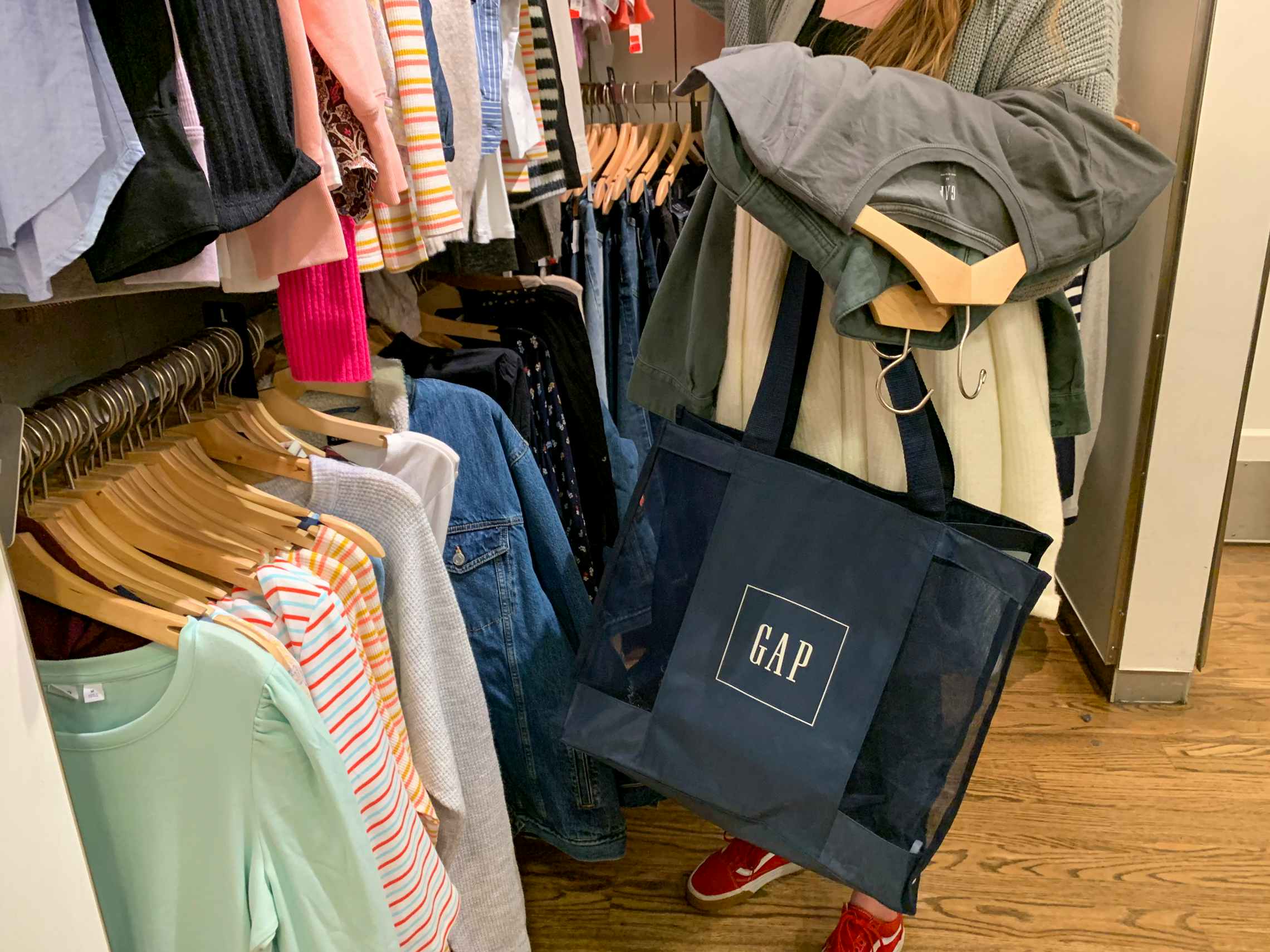 A woman shopping searching a clearance rack with clothing in her arms.