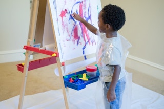 A child painting on an easel.