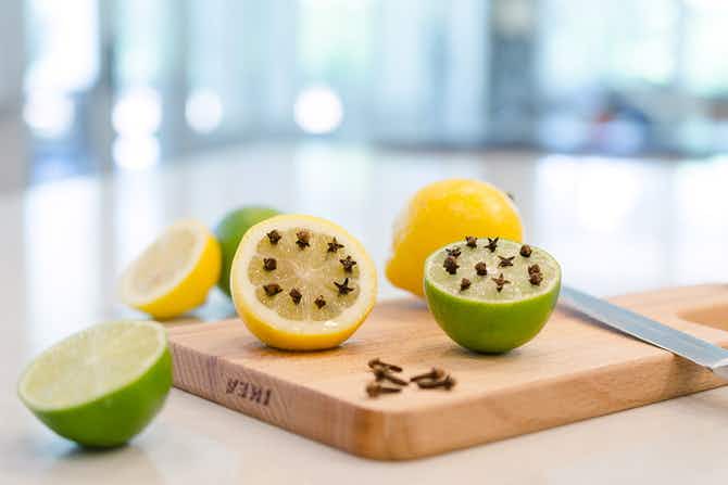 Whole cloves stuck in halved lemons and limes on a cutting board