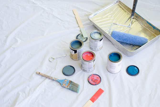 A drop cloth with cans and a tray of paint.