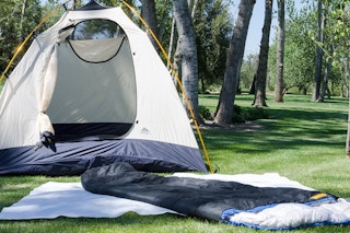 Sleeping bag on the ground next to a tent.