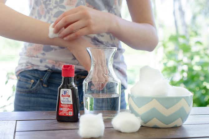 Woman applying a cotton ball with vanilla extract bug repellent to her arm