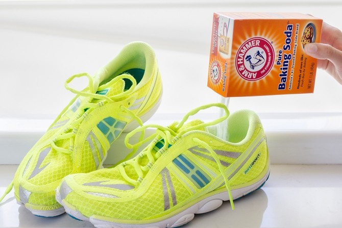 Someone sprinkling baking soda in shoes to absorb odors.