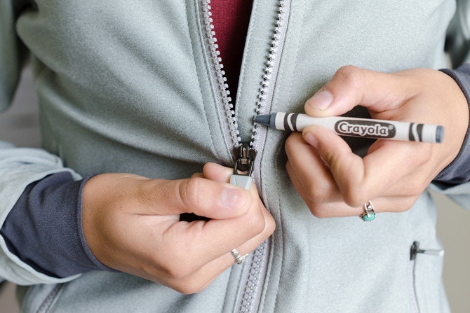Free a caught zipper by coloring the teeth on both sides with a crayon.