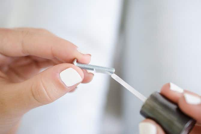 someone putting a thin coat of nail polish on screw