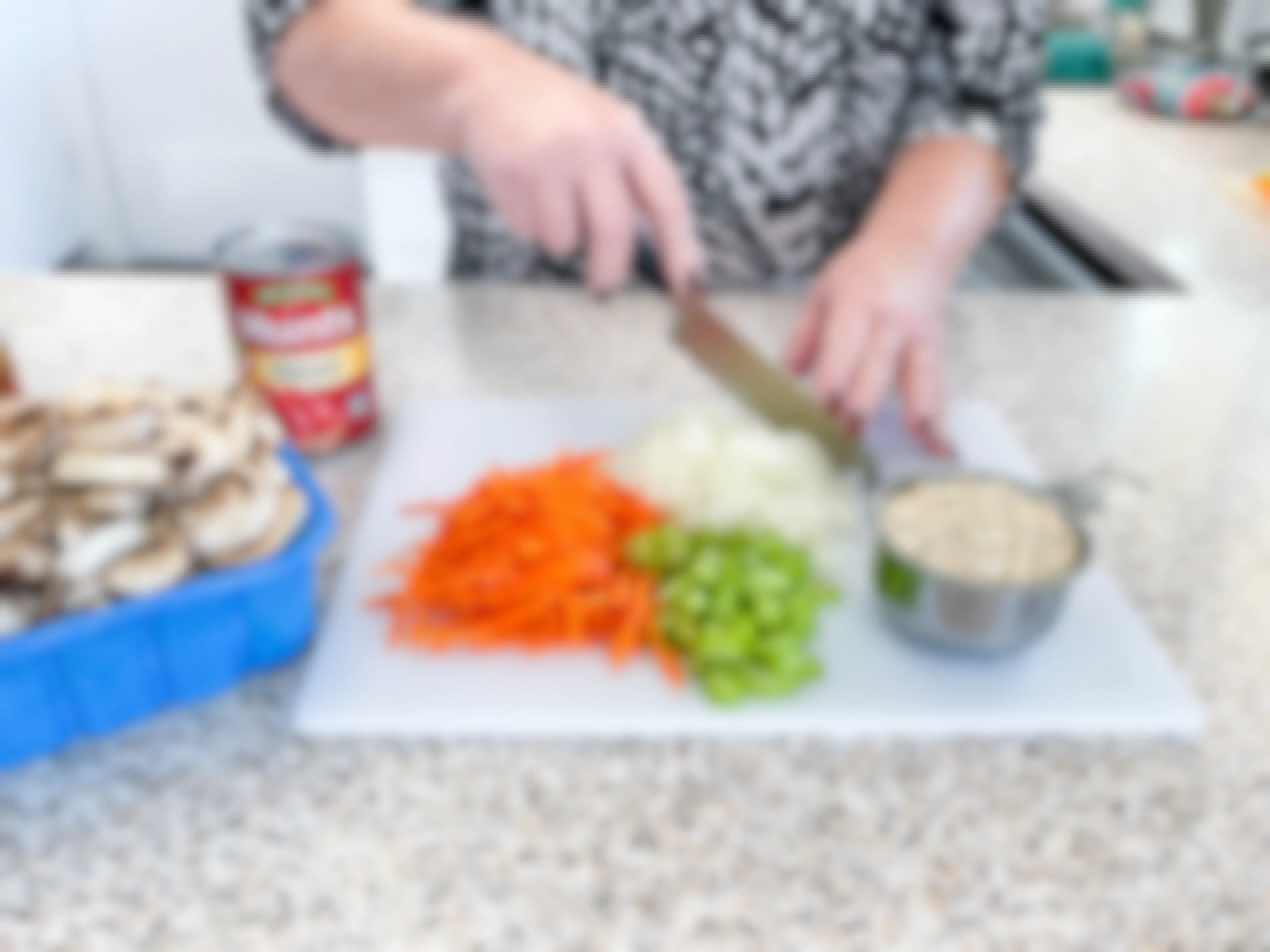 A woman preparing ingredients, chopping vegetables on a cutting board.