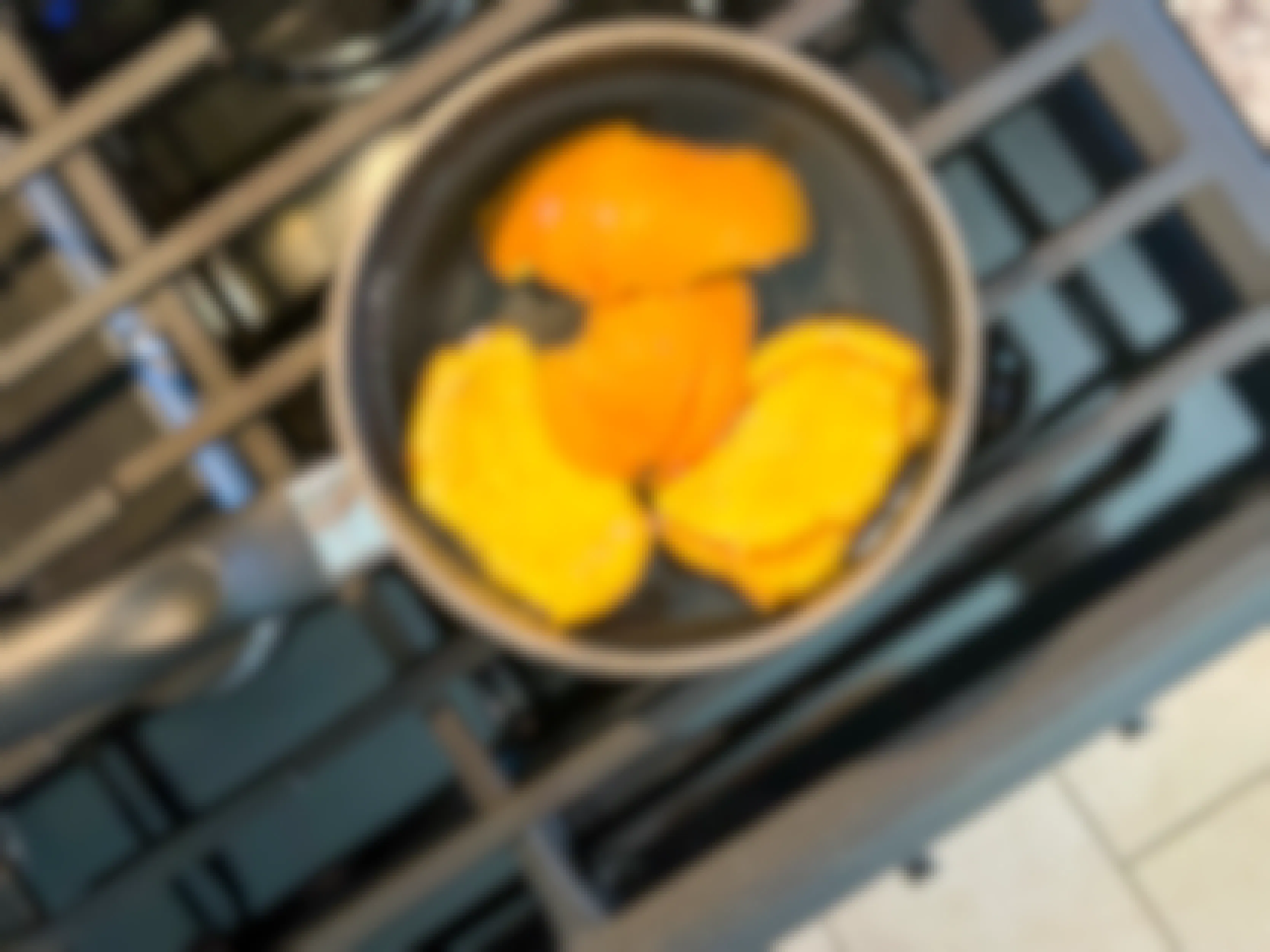 orange peels in a pot with water sitting on a stove