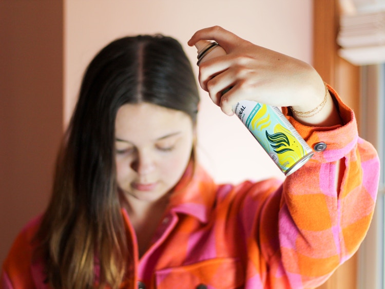 person using dry shampoo on their hair