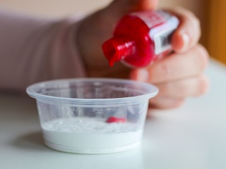 person adding red nail polish to corn starch