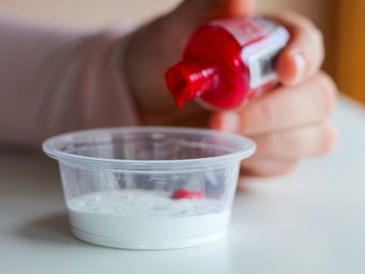 person adding red nail polish to corn starch