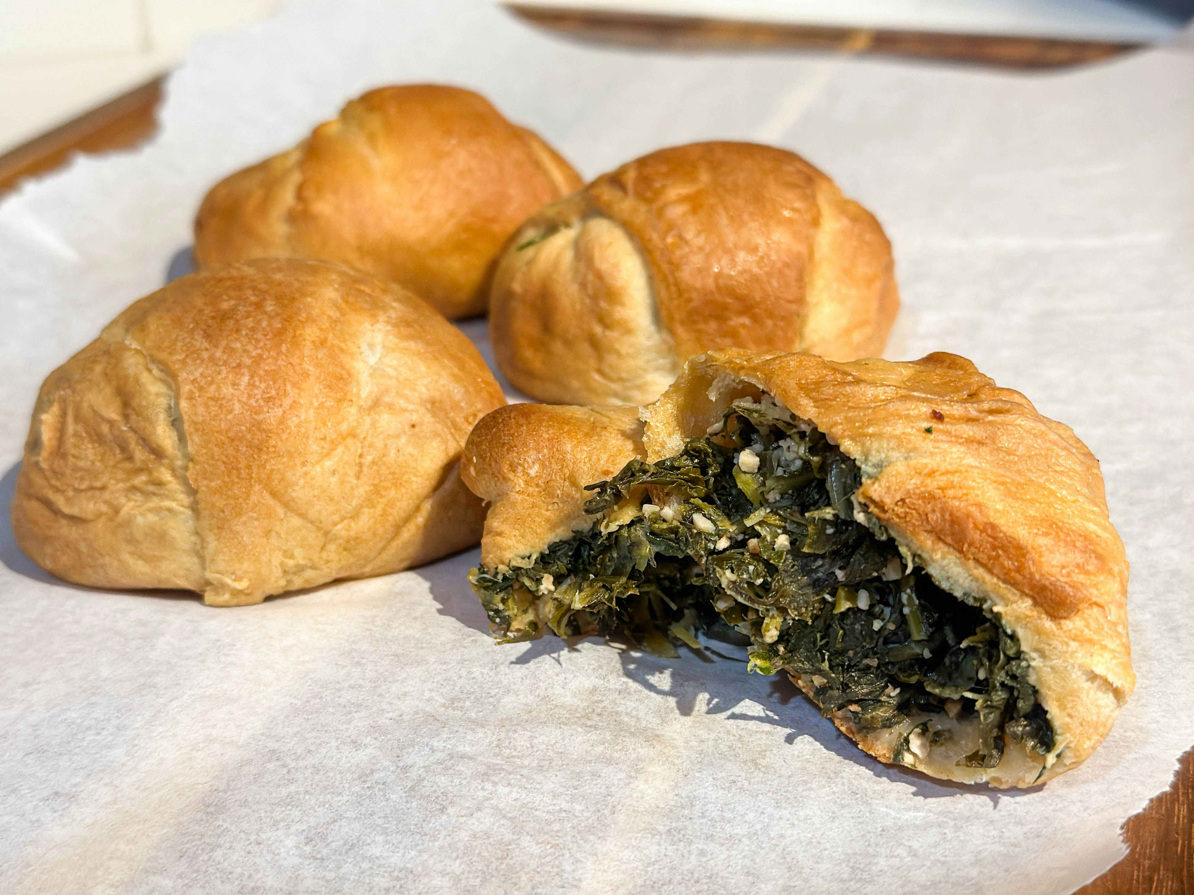 a crescent roll filled with spinach and feta on parchment paper 