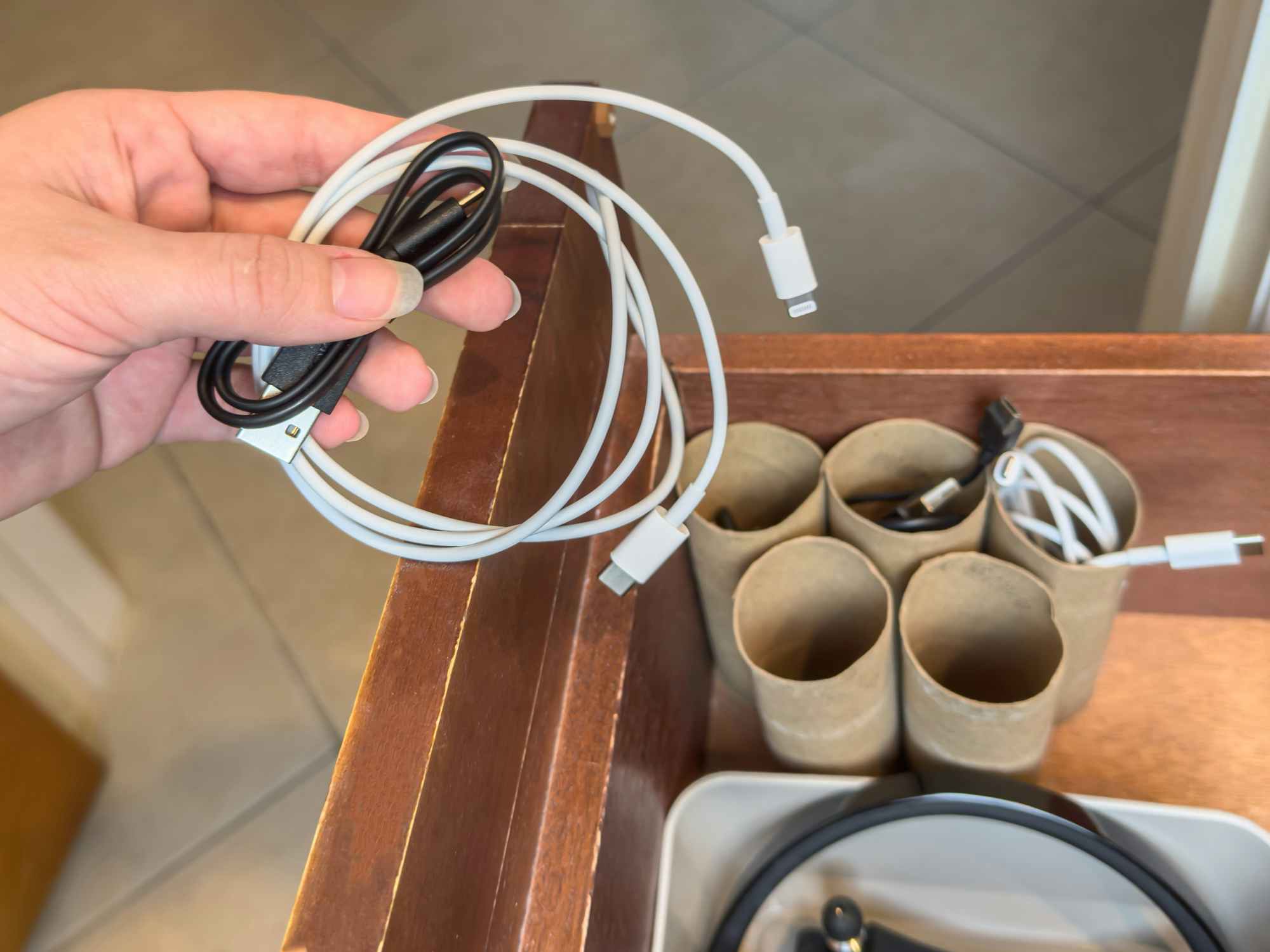Someone organizing their cords into empty toilet paper tubes set up in a drawer