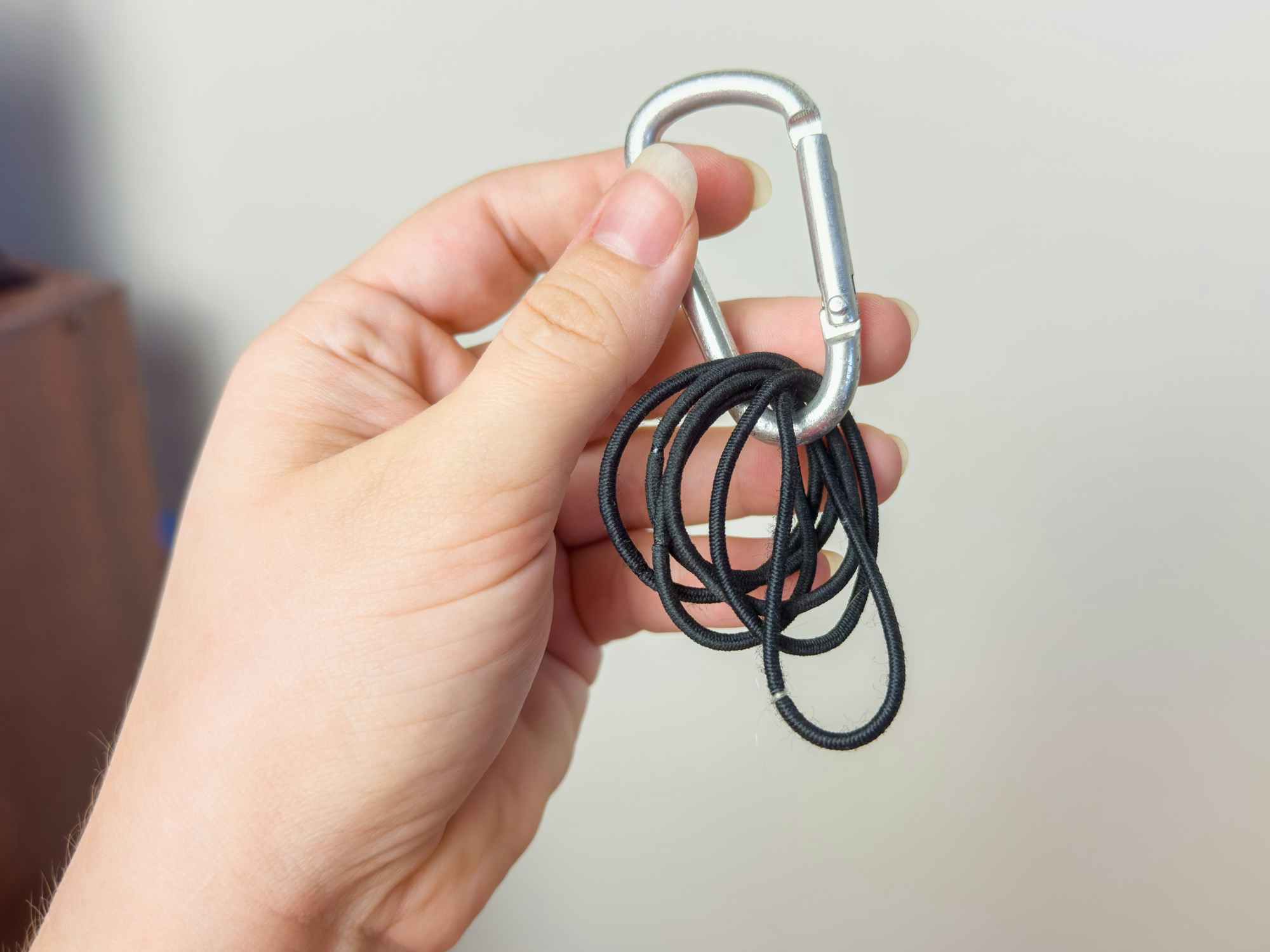 Someone holding up a carabiner with several hair ties clipped onto it