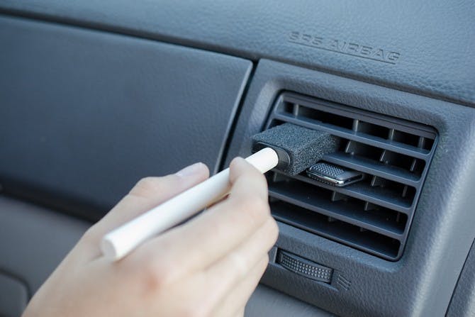 Someone dusting an auto A/C vent with a foam craft brush. 