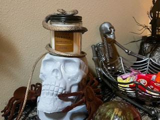 a skull candle holder with a candle and halloween decor on a table