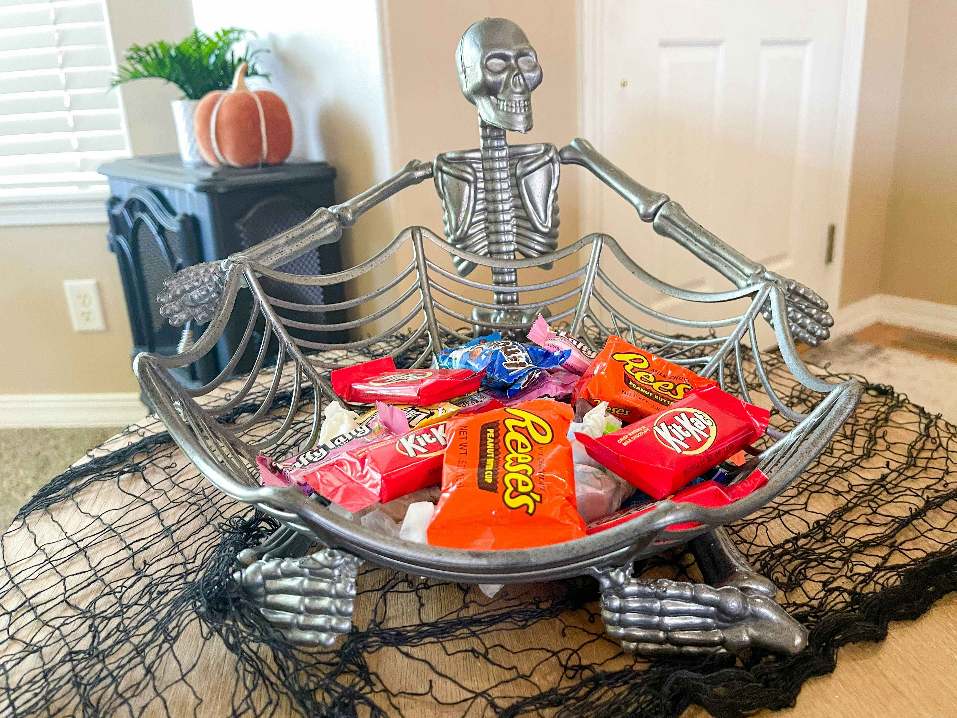 a skeleton candy basket with candy inside sitting on an end table