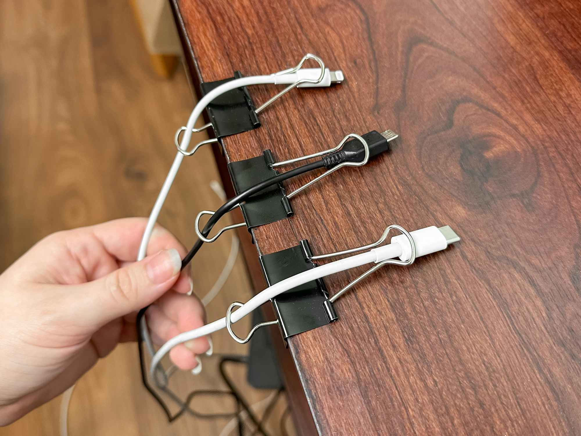 Someone organizing charging cords with binder clips
