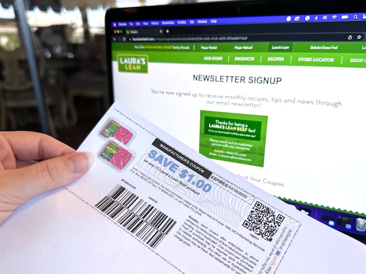 Someone holding a printed coupon for Laura's Lean Beef in front of their email newsletter signup webpage