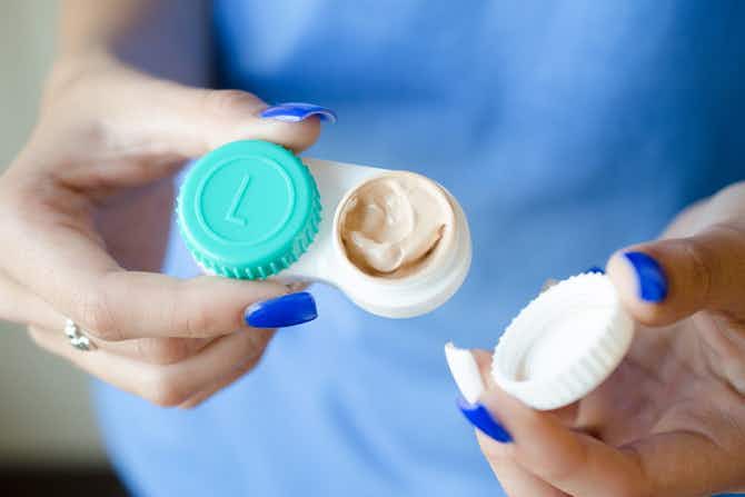 Someone holding a contact lens case with one side open showing makeup